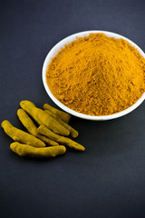 Turmeric powder in white bowl with roots or barks
