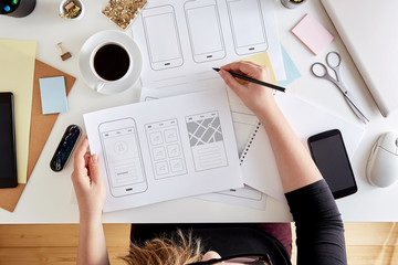 Top view of young UX graphic designer planning out the structure of a mobile application....