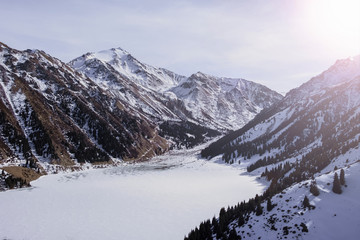 Fototapeta na wymiar Beautiful mountains with frozen lake in sunny winter day. BAO or big almaty lake.