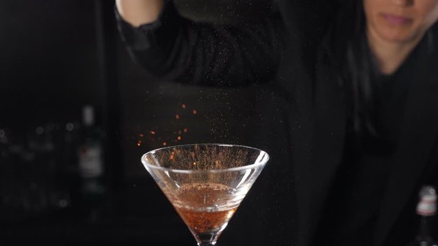 Bartender sets fire to cocktail, burning cinnamon in alcohol drink on black background. Flames in cocktail glass in slow motion, burning cinnamon in alcohol drink, barman makes drink. Full hd footage
