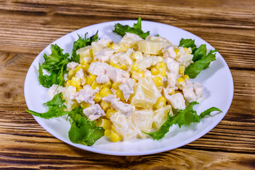 Festive salad with chicken breast, canned pineapple, cheese, sweet corn and mayonnaise on wooden table