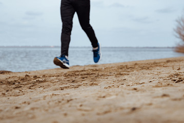 Young man in sportswear jogging on the beach