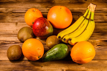 Still life with exotic fruits. Bananas, mango, oranges, avocado, grapefruit and kiwi fruits on wooden table