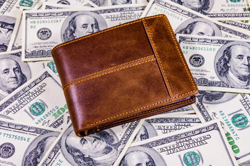 Closed brown leather wallet on the one hundred dollar banknotes