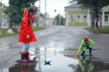 children brother and sister play autumn rain / October weather little children walk in the city