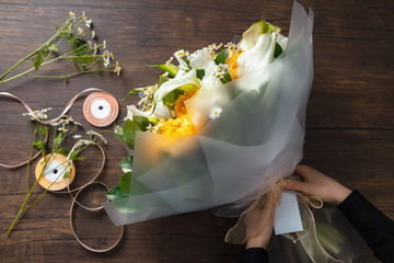 Florist at work: woman making fashion modern bouquet of different flowers on wooden background. Masterclass. Gift for bride on wedding, mother's, woman's day. Romantic spring fashion. Bright colors.