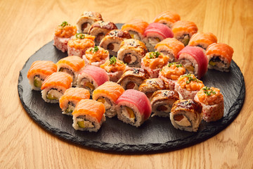 Various kinds of sushi roll set served on black stone. Japanese food