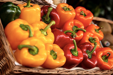 Closeup of a group of Bell Peppers, red, yellow, orange and green in a wicker basket at the market 