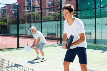 padel players of different generations playing padel court