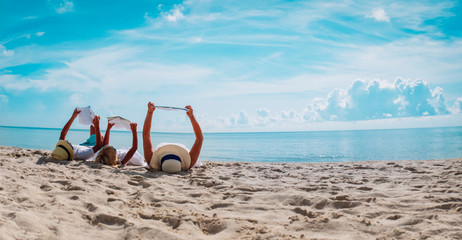 mother with kids reading books at beach, family on vacation