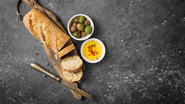 Loaf of bread with spicy olive oil and old rusty table-knife