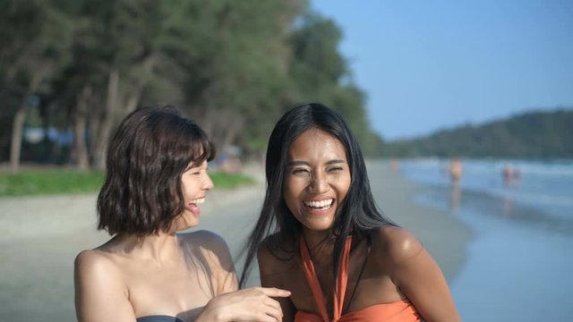 Holiday concept. Two beautiful girls in bikinis are fun pointing at the beach. 4k Resolution.