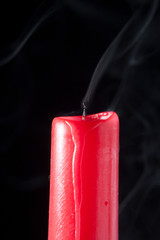 red candle extinguished and with smoke on black background