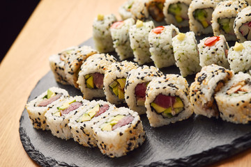 Various kinds of sushi roll set served on black stone. Japanese food