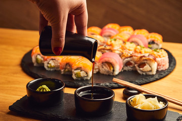 Hand  pouring soy sauce (Shoyu) from little jug into the bowl before eating japanese food such as sushi roll © bondvit