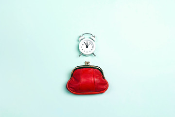 Purse with alarm clock on blue background.