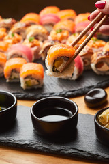Hand with chopsticks soaks sushi in soy sauce. Tasting Japanese food.