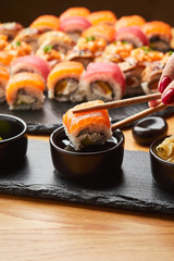 Hand with chopsticks soaks sushi in soy sauce. Tasting Japanese food.