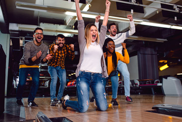 Group of friends enjoying time together laughing and cheering while bowling at club. - obrazy, fototapety, plakaty