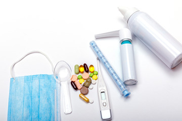 Treatment of colds and flu. Various medicines, a thermometer, sprays from a stuffy nose and a pain in a throat on a white background. Copy space for text. Medicine flat lay concept.