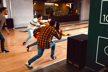 Obraz premium Group of friends enjoying time together laughing and cheering while bowling at club.