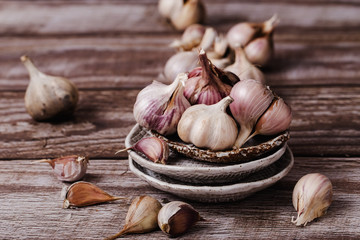 The bulbs of garlic, on ceramic plate on a wooden table, brown background