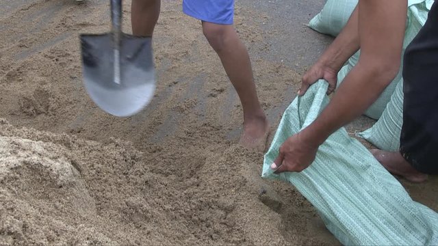 Volunteers filling bags with sand to build a sandbag dike for flood protection ( close up )
