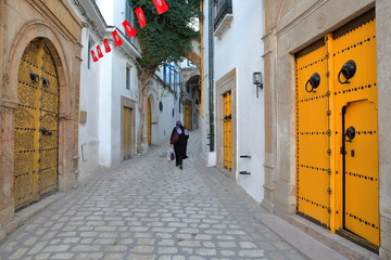 Typical cobbled and narrow street (Dar el Jeld street) with colorful doors, columns and arcades...