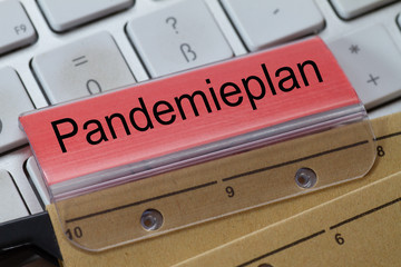 The German word for pandemic plan can be seen on the label of a brown hanging folder. The hanging...