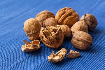 Close up at seed of Walnut (Juglans regia) and uncraked in wooden bowl on blue background. Favorite for snack and very delicious. Have a lot of omega 3 for brain. Healthy food concept.