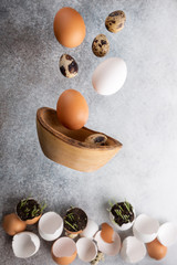 Fototapeta na wymiar Flying chicken and quail eggs and eggshells on gray background. Levitation food, happy Easter concept.