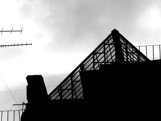 silhouette of triangle glass tower at the old building roof