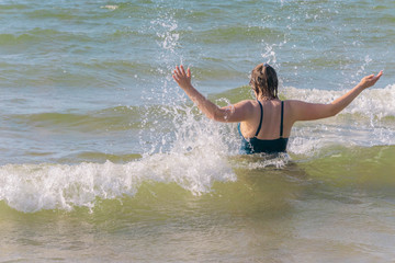 Woman doing splashes of water in waving sea