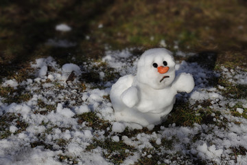 Snowman is melting in the sun. Thaw, warm winter, early spring, global warming, climate change....
