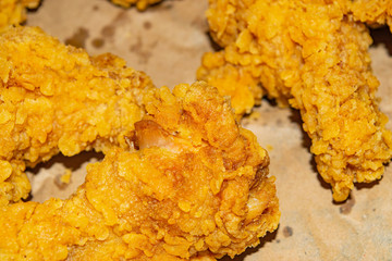 Chicken wings fried in breadcrumbs on a grey paper background. Close up.