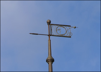 Old iron weather vane on the roof of the house
