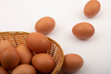 Chicken eggs in a wicker basket and scattered on a white background. Close up.