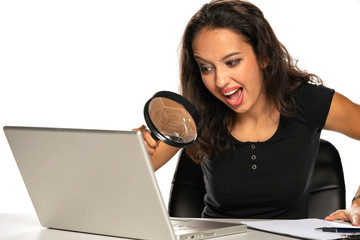 woman with laptop looking trough the magnifying glass