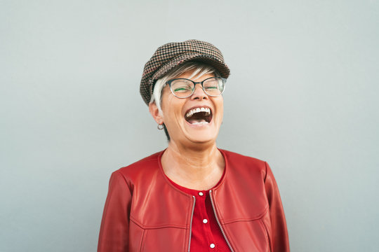 Happy senior woman laughing outdoor - Trendy mature person having fun during retired time - Elderly people lifestyle concept