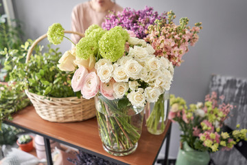 Floral shop concept . Florist woman creates flower arrangement in a wicker basket. Beautiful bouquet of mixed flowers. Handsome fresh bunch. Flowers delivery.