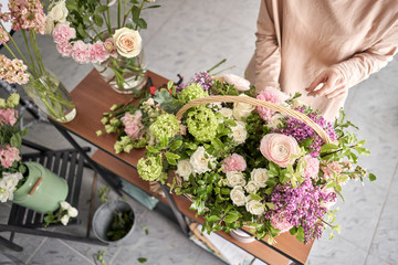 Floral shop concept . Florist woman creates flower arrangement in a wicker basket. Beautiful bouquet of mixed flowers. Handsome fresh bunch. Flowers delivery.