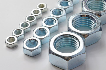 New, chrome new nuts of different sizes on a white background.