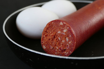 a small pan next to beef sausage and egg, turkish cuisine and sausage,