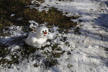 Snowman is melting in the sun. Thaw, warm winter, early spring, global warming, climate change...