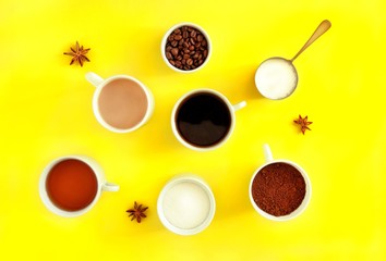 Various types  ceramic white cups of coffee, tea with sugar, cream and star anise on a bright yellow background. Coffee break concept. Top view, flat lay.