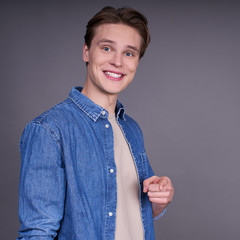 Happy smiling handsome man points finger straight.