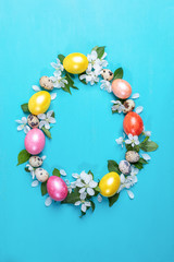 Colored hen eggs, quail eggs and white Apple tree flowers laid out as Easter egg on turquoise painted wooden background.