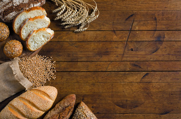 Assortment of bread and wheat on wooden table.