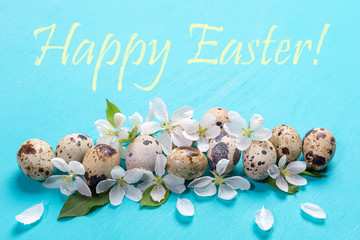 Festive Easter greeting card with quail eggs, white Apple tree flowers and words Happy Easter on...