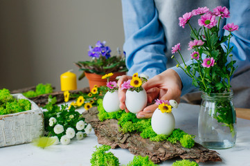 Woman holding Easter decoration with eggs and flowers on pine bark